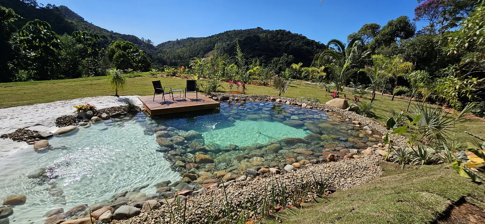 Piscina natural da Vila Pinheiro, com deque de madeira e a serra ao fundo