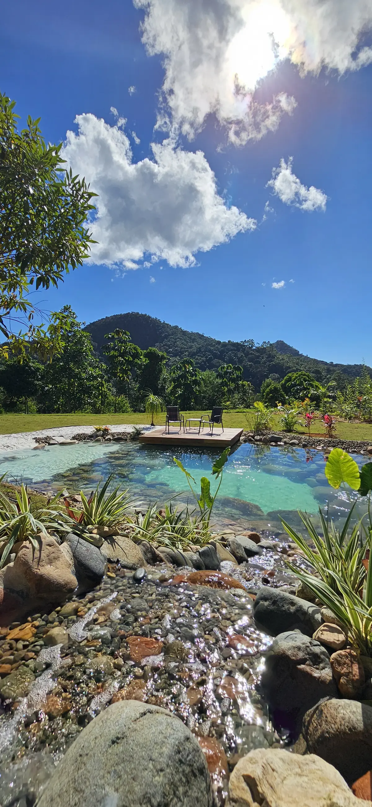Piscina natural entre as pedras, com as montanhas e o céu ao fundo