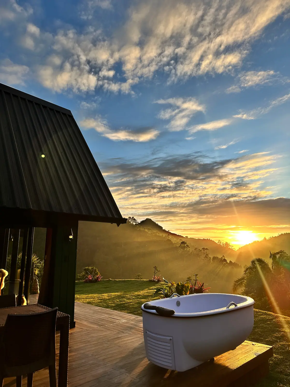 Banheira no deque da Cabana Jasmim ao nascer do sol, com a serra ao fundo